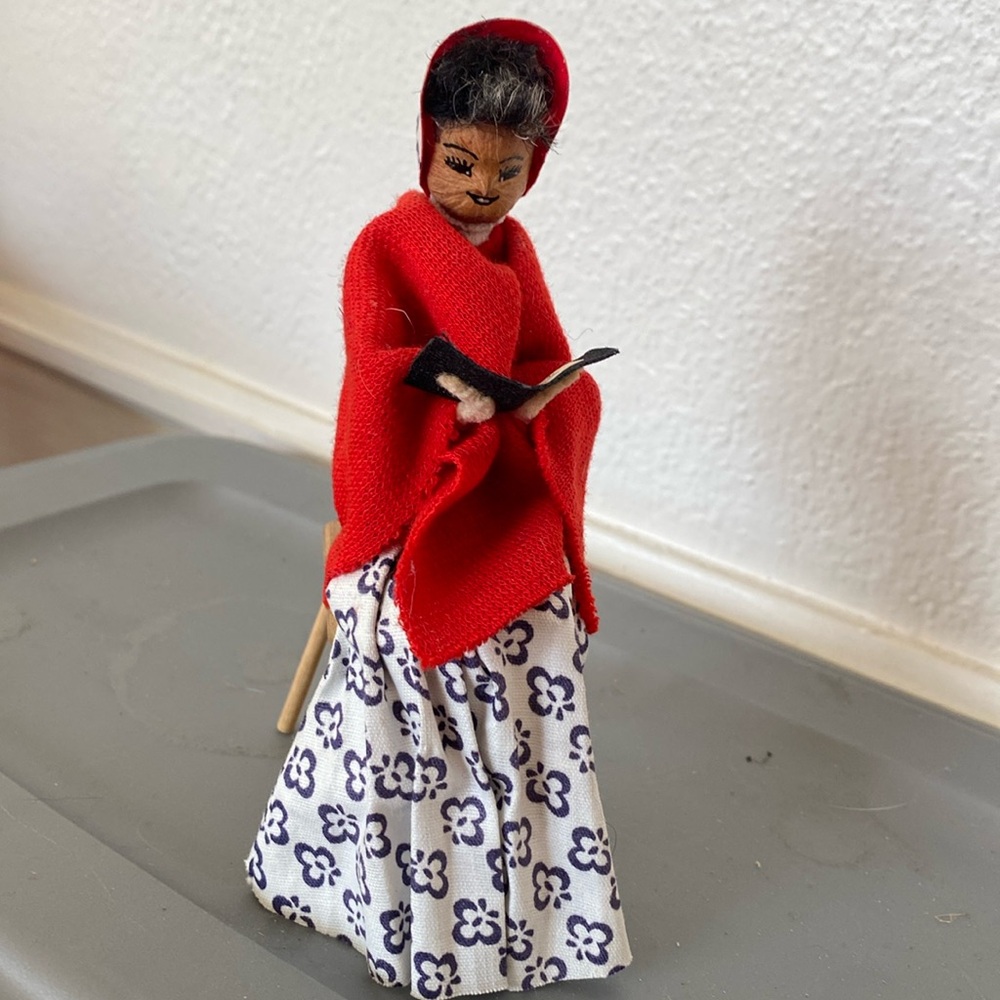 Pretty little folk art lady reading a book. Maybe the Bible. Maybe nut for face.